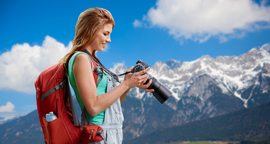 旅行,旅游摄影快乐的轻妇女背包相机拍摄阿尔卑斯山背景女人带着背包相机阿尔卑斯山上女人带着背包相机阿尔图片