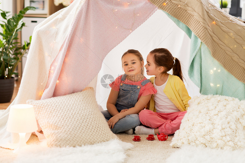 童潮湿的快乐的小女孩玩茶话会与玩具陶器孩子们的帐篷家里分享秘密小女孩家孩子们的帐篷里玩茶话会小女孩图片