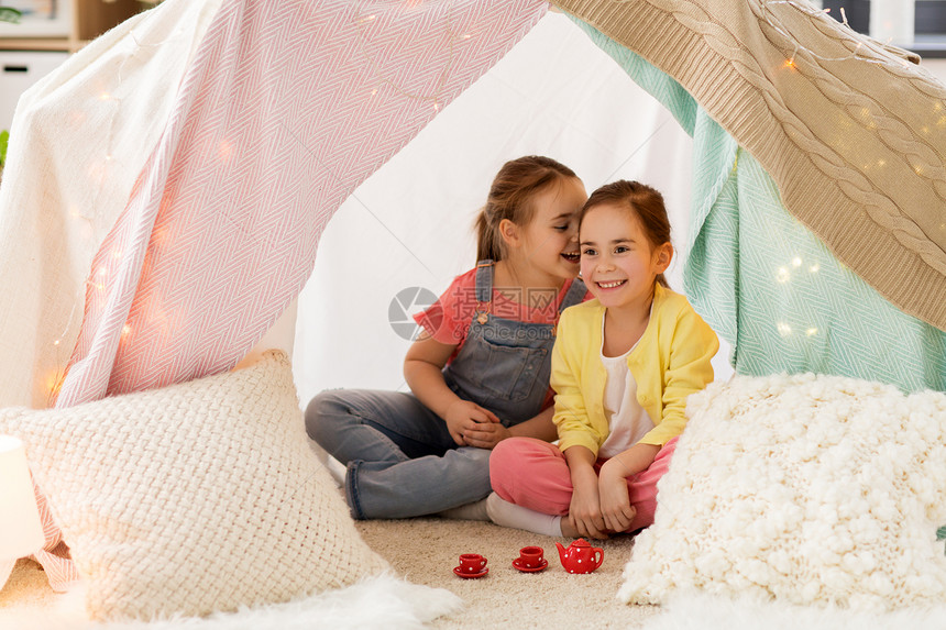 童潮湿的快乐的小女孩玩茶话会与玩具陶器孩子们的帐篷家里分享秘密小女孩家孩子们的帐篷里玩茶话会小女孩图片