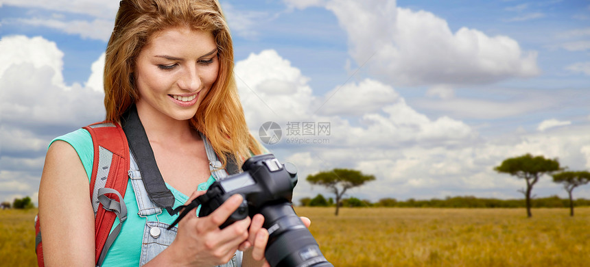 旅行,旅游摄影快乐的轻妇女背包相机拍摄非洲草原背景女人带着背包相机萨凡纳上空女人带着背包相机萨凡纳图片