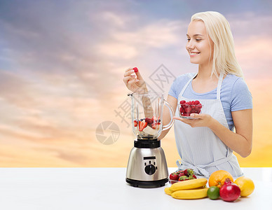 微笑的女人正在使用榨汁机背景图片