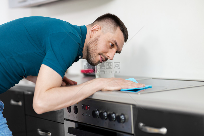 家庭人的男人擦拭桌子与布清洁炊具家庭厨房家里厨房里抹布清洁炊具的男人家里厨房里抹布清洁炊具的男人图片
