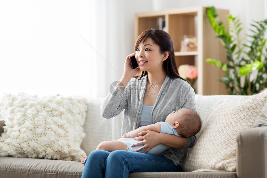 家庭,技术母亲的快乐的微笑的轻亚洲母亲与熟睡的婴儿打电话家里的智能手机母亲带着婴儿家里打电话给智能手机母亲图片