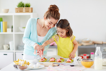 家庭,烹饪人的母亲小女儿家庭厨房用奶油霜制作装饰纸杯蛋糕妈妈女儿家纸杯蛋糕背景图片