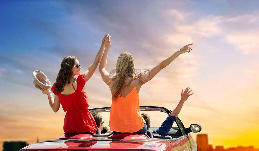 暑假,公路旅行旅游快乐的朋友驾驶敞篷汽车挥手天空背景朋友们日落时开着敞篷车图片