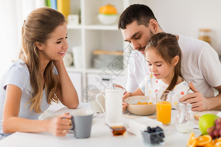 快乐的父母与女儿在家里幸福的吃早餐背景图片