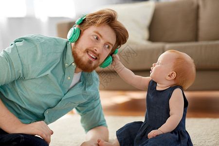 家庭,父亲人的快乐的红头发父亲带着耳机小女儿家父亲戴着耳机,女儿家里图片