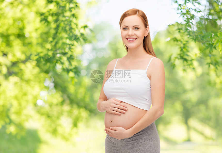 怀孕,母亲,人期望的快乐的孕妇触摸她裸露的腹部绿色的自然背景快乐的孕妇抚摸她赤裸的腹部图片