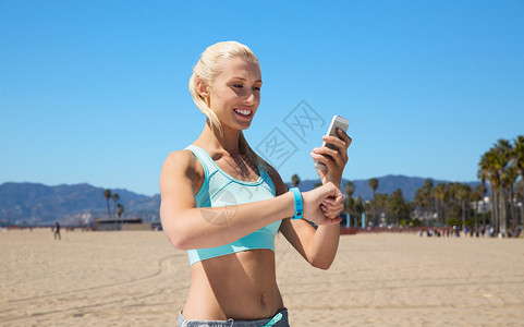 减肥跟踪记录表运动,技术健康的生活方式微笑的轻妇女与健身跟踪智能手机锻炼威尼斯海滩背景加利福尼亚快乐的女人健身追踪器智背景