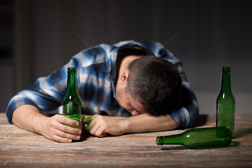 酒精的男酒精与啤酒瓶躺桌子上晚上睡觉晚上桌子上放啤酒瓶的醉汉图片