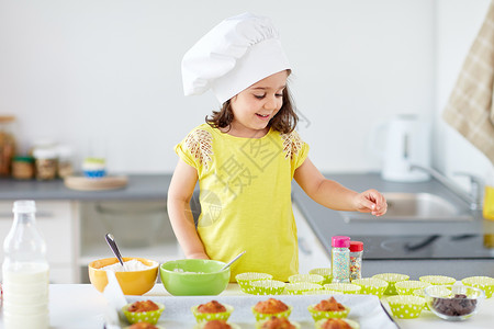 家庭,烹饪人的小女孩厨师烤松饼纸杯蛋糕洒家里厨师里的小女孩家烤松饼图片