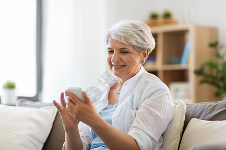 养老金领取者应用程序技术,沟通人的快乐的老年女子与智能手机家里快乐的高级女人家里智能手机背景