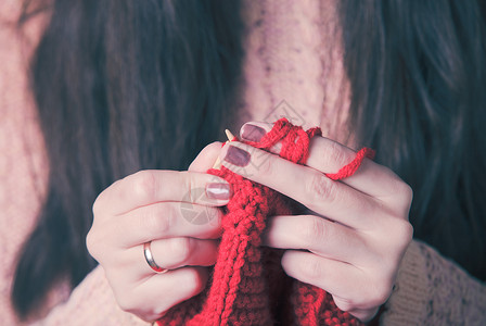 握住针头编红色温暖夹克的手女手针毛衣背景图片