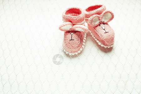 婴儿战利品针粉红色婴儿靴与兔子口吻纺背景针婴儿靴背景