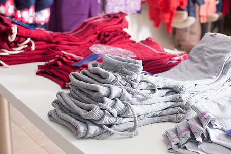 红色裤子,成排地堆放服装店的白色架子上时髦的服装店图片