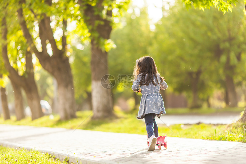 女孩积极休息个阳光明媚的夏天,小女孩城市公园里骑滑板车女孩积极休息图片