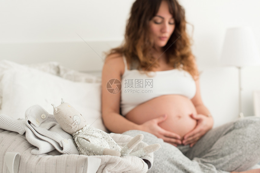 孕妇摸她的肚子快乐的孕妇坐家里摸着肚子图片