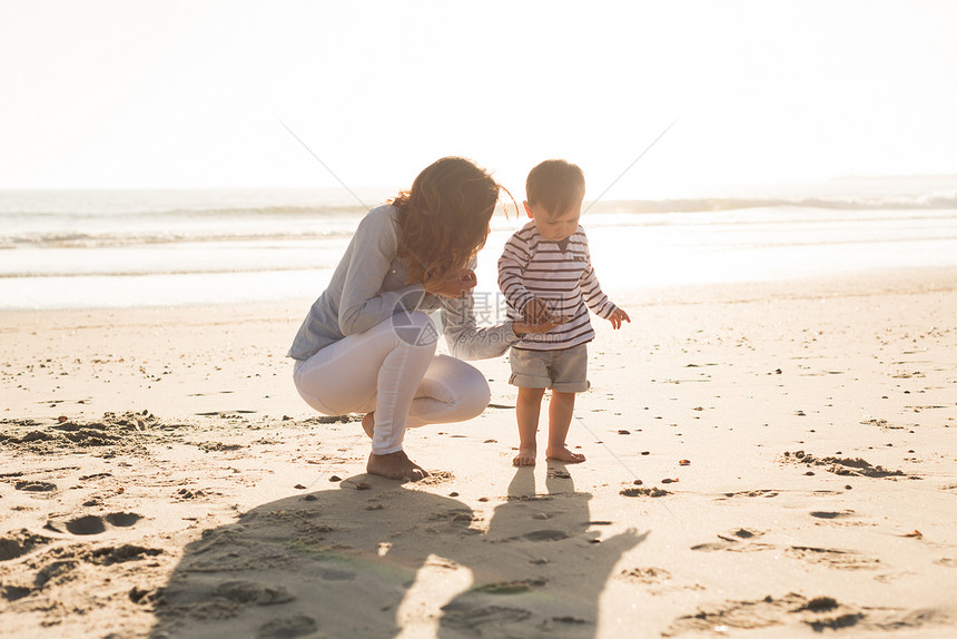 妈妈她的孩子海滩上轻的母亲她的孩子探索海滩图片