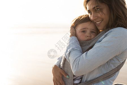 妈妈带着孩子母亲带着麦格宝宝海滩上抱着蹒跚学步的孩子图片