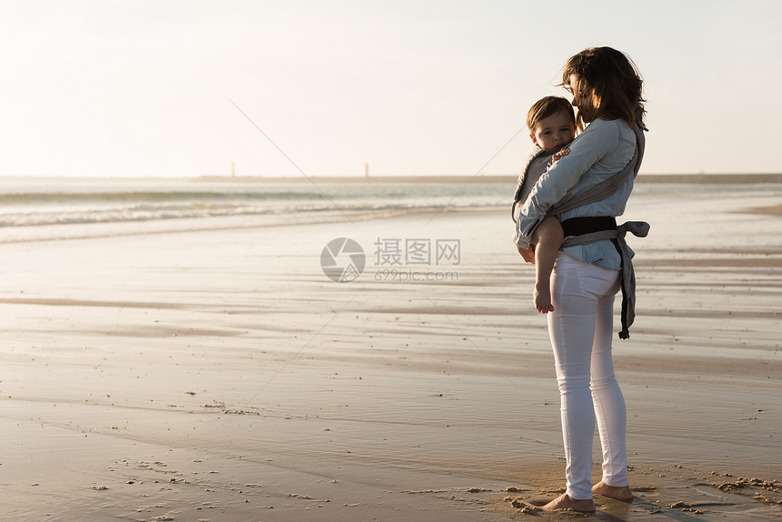 妈妈带着孩子母亲带着麦格宝宝海滩上抱着蹒跚学步的孩子图片