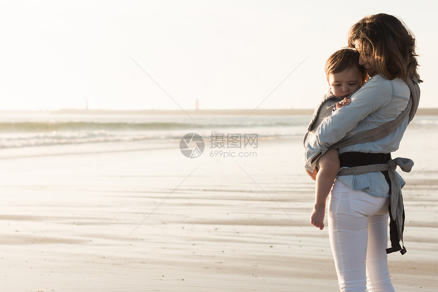 母亲带着麦格宝宝海滩上抱着蹒跚学步的孩子图片