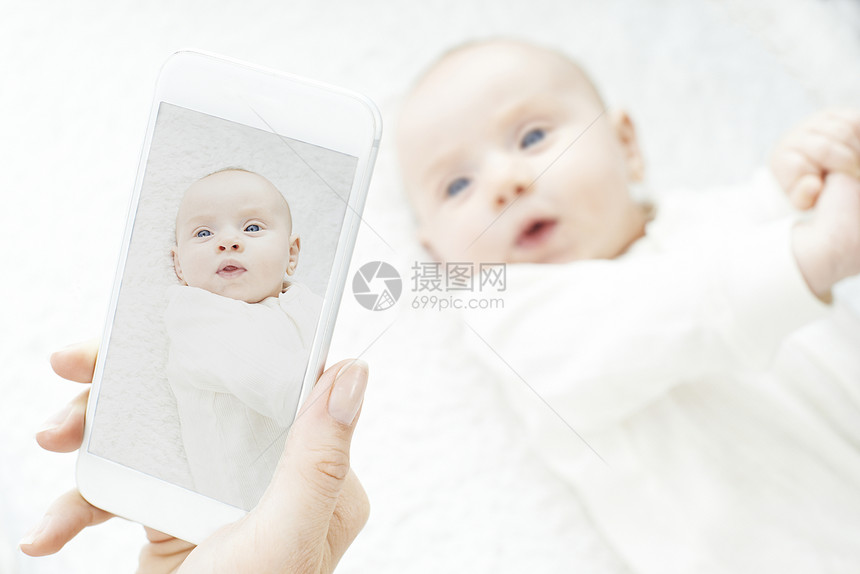 妈妈手机上给女婴拍照图片