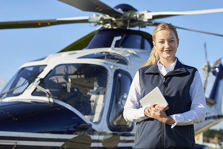 女飞行员站直升机前用数字平板电脑的肖像图片