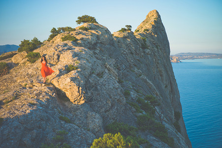 户外生活方式照片,女人穿着红色连衣裙岩石上行走旅行背景旅游业图片