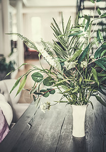 客厅正视图舒适的现代家庭内部与桌子花瓶与绿色热带植物客厅背景,正视图背景