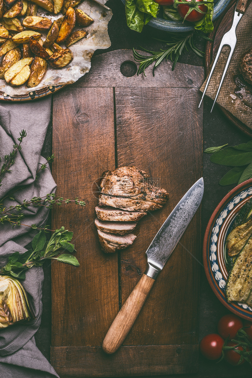 切片油炸猪肉菜刀砧板上与烤土豆乡村桌子上,顶部视图图片