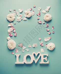 白色单词的框架爱与淡玫瑰花瓣上的绿松石蓝色背景,顶部的现代最布局图片