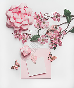 粉红色贺卡漂亮的粉彩贺卡模拟与鲜花装饰,心,小礼品盒蝴蝶结白色的桌子背景,顶部视图,平躺婚礼邀请布局母亲节背景