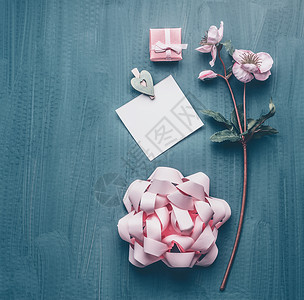 女问候背景与装饰花,蝴蝶结,粉红色礼品盒卡片模拟,顶部查看女日母亲日布局图片