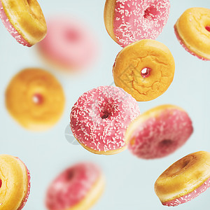 坠落飞行粉红色釉甜甜圈与洒淡蓝色背景,创造的布局模式图片