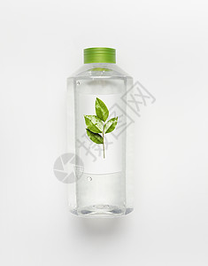 透明液体瓶,绿色盖子清洁自然水与绿叶品牌模拟白色书桌背景,顶部视图图片