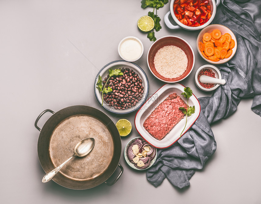 碗与配料平衡的锅餐与豆类,碎肉,大米各种切割蔬菜烹饪锅与勺子灰色背景,顶部视图图片