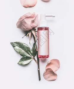 粉红色玫瑰必可少的化妆品瓶与品牌模拟玫瑰花花瓣白色背景,顶部视图图片