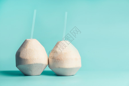 新鲜椰子鸡尾酒与粉红色饮料吸管蓝色绿松石背景,正视图健康的椰子水背景图片