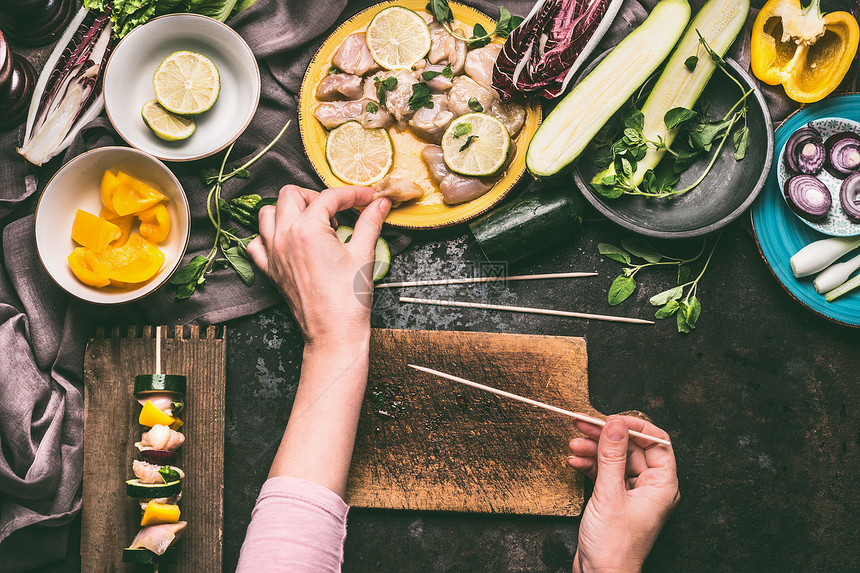 肉类蔬菜烤肉准备女手块鸡肉黑暗的厨房桌子背景与碗与配料烧烤,顶部视图图片
