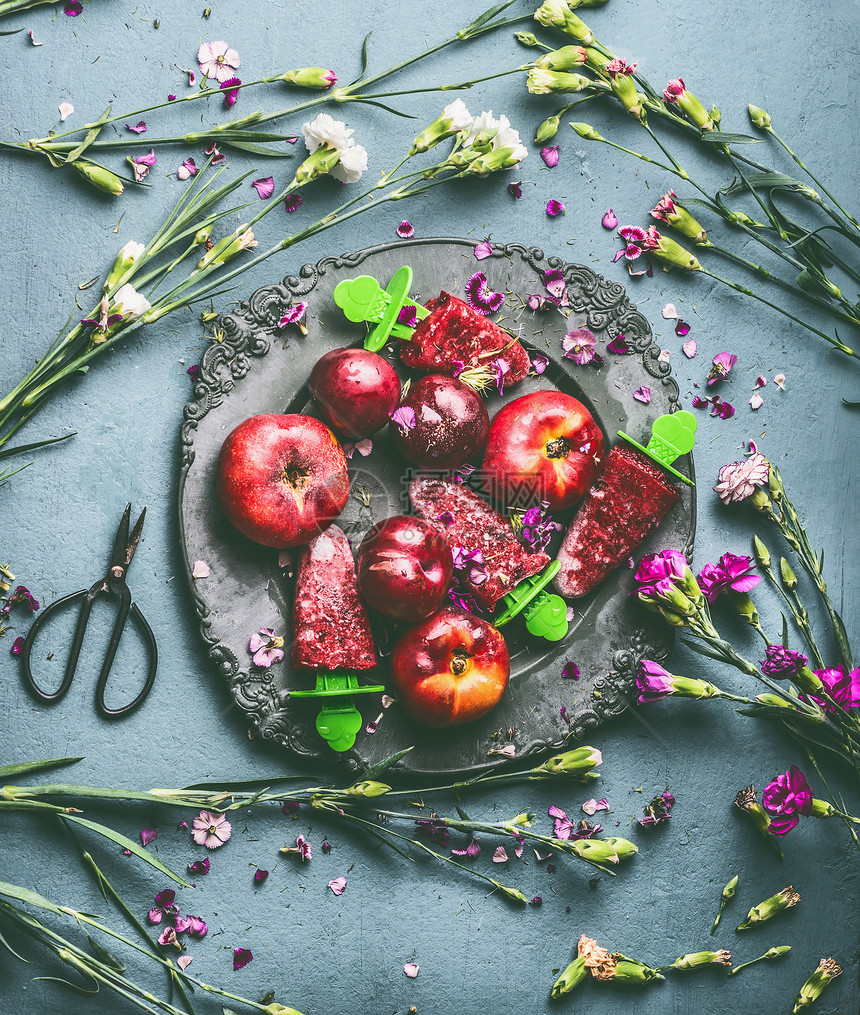 盘子与自制的红色水果冰淇淋冰棒冷冻果汁乡村厨房桌子背景与花园花卉配料,顶部查看季节夏季机食品存图片
