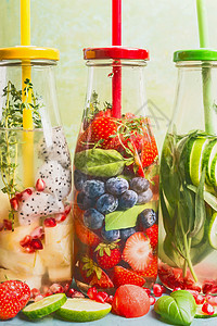 注入水的瓶子与饮料吸管配料,正视图用五颜六色的水果浆果草药调味的水夏季饮料健康干净的排饮料图片