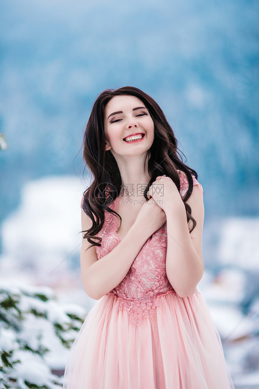 冬山背景上栗色头发蓝色眼睛粉红色连衣裙的女孩图片