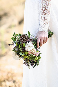 新娘的花来自圆锥形棉花,靠近新娘的手,花边礼服森林背景图片
