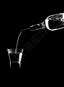 桌子上的个杯子里,把白葡萄酒瓶子里倒进黑色背景的饮水机里图片