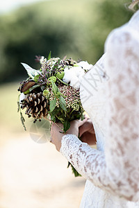 新娘的花来自圆锥形棉花,靠近新娘的手,花边礼服森林背景图片