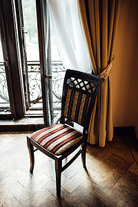 切斯特菲尔德窗户附近橡木地板上的老式椅子背景