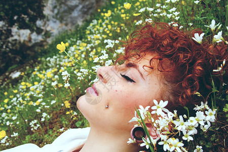 个轻的红头发女人睡片花丛中背景图片