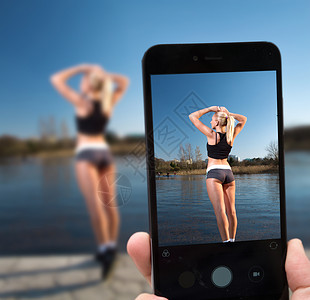 条河的背景上,智能手机上拍摄位女运动员模特给个女运动员拍照图片