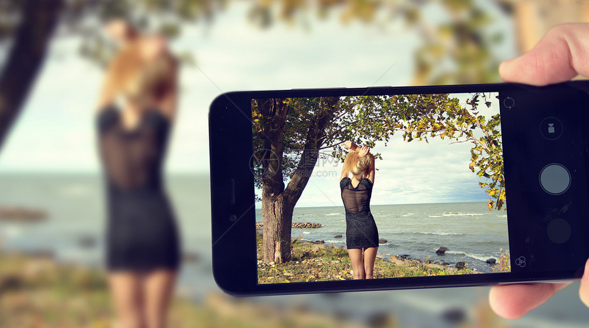 博主智能手机上拍摄海边女孩的照片秋天的波罗的海图片
