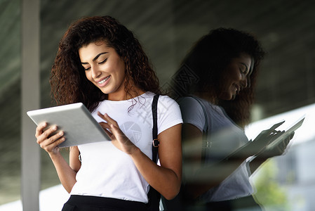 轻的黑人女子看着她的数字平板电脑户外图片